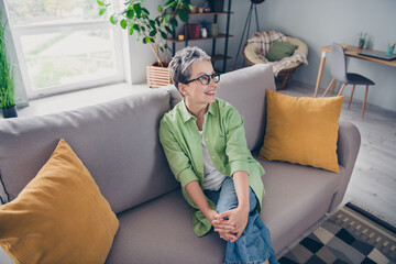 Obraz premium Portrait of dreamy happy pensioner attractive pensioner woman looking far away hug her knees indoors inside office smiling good mood