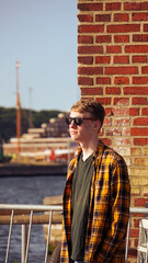 Teenager with sunglasses looking at a harbour, portrait - Stock photo