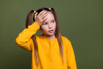 Photo of upset schoolgirl with ponytails wear yellow pullover look empty space hand on forehead...
