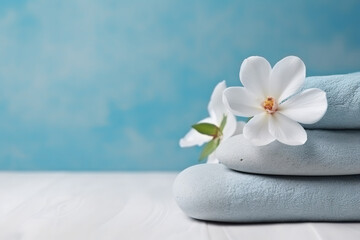 Obraz na płótnie Canvas Zen stones flowers and towels on light blue background convey spa and wellness concept Promote