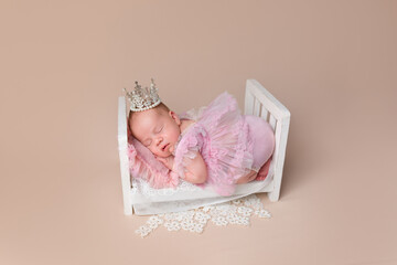Fototapeta na wymiar Cute newborn baby wearing a dress and crown. Little Princess. Newborn girl in a crib. Newborn's first photo session