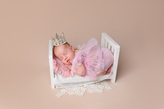 Cute newborn baby wearing a dress and crown. Little Princess. Newborn girl in a crib. Newborn's first photo session