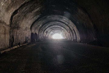 Old underground road tunnel inside mountain. Light at the end of tunnel - obrazy, fototapety, plakaty