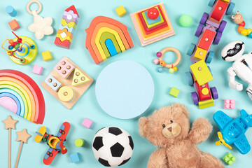 Empty round platform podium stand, with teddy bear, robot and many natural wooden ecological sustainable educational children toys. Baby kid toys on light blue background. Top view, flat lay
