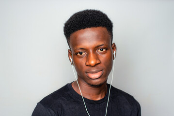 Happy cheerful young African gen Z isolated on white background. Funny confused state of mind plugs earpiece to ear with optimistic look - obrazy, fototapety, plakaty