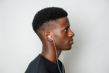 Side Profile view of Young African gen Z isolated on white background plugs earpiece to ear