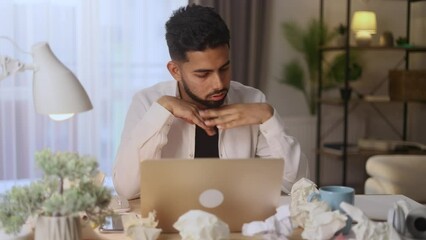 Portrait of exhausted tired young man student or freelancer with failed ideas while take break at home workplace Tired indian male with creative block or lack of inspiration throw away papers indoors	