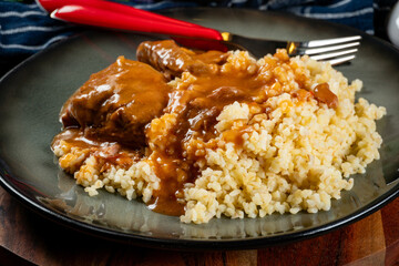 Braised pork neck in own sauce served with barley groats and salad.