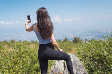 Young Woman using mobile phone in the Summer Mountain .Woman making selfie 