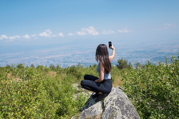 Young Woman using mobile phone in the Summer Mountain .Woman making selfie 