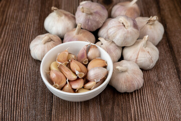 Big and small heads of garlic on a wood grain background