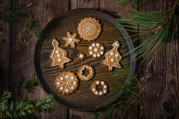 Gingerbread cookies decorated with icing on table surrounded by lights and pine 