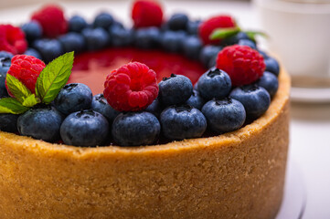 close-up of cheesecake with cream filling, decorated with fresh berries, blueberries and raspberries, festive New Year's cake, Christmas	
