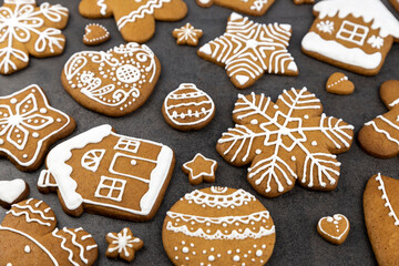 Christmas gingerbread cookies with icing on a gray background in the shape of a house and a gingerbread man, a tree and balls, stars and snowflakes and hearts.