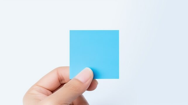 a blue post it note on a finger on a white background