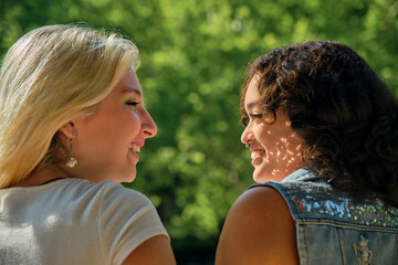 Latin American and Caucasian lesbians in profile smiling looking at each other in love