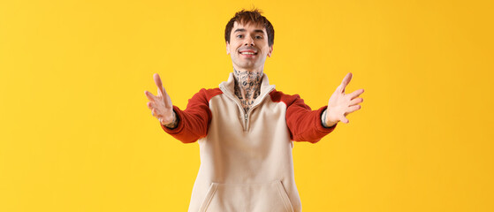 Young man opening arms for hug on yellow background