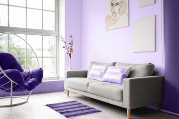 Interior of modern room with comfortable grey sofa and armchair
