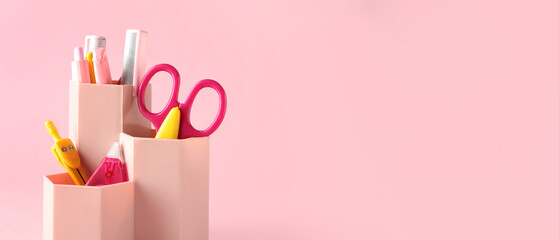 Holder with different stationery on pink background with space for text