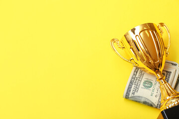 Gold cup with money on yellow background
