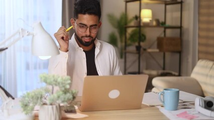 Excited focused motivated young man student with glasses listening interesting exciting online lecture with enthusiasm on laptop computer and make notes at home Distance remote education concept
