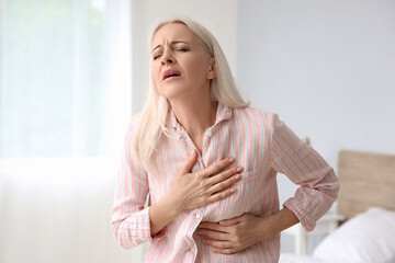Mature woman having heart attack in bedroom