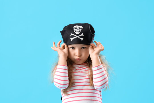 Cute little girl dressed as pirate on blue background