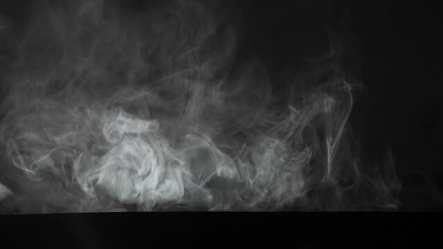 In the frame on a black background is thick, dense smoke, a fog that is spreading. It illuminates a ray of light. Abstract image is used for picture screensavers