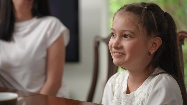 In a playful, comic form, the mother limits her daughters consumption of sweets. Mother and daughter spend leisure time in a modern house sitting at the table