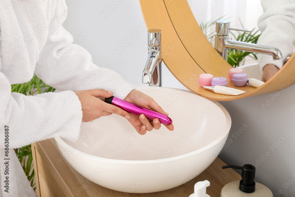 Wall mural Woman washing vibrator over sink in bathroom, closeup