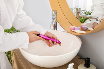 Woman washing vibrator over sink in bathroom, closeup