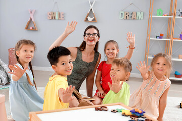 Little children with nursery teacher in kindergarten