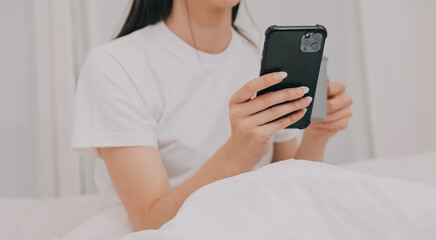 Efficient Young Millennial Girl Sitting on a Bed in the Morning, Uses Laptop Computer and Eats Croissants and Drinks Coffee for Breakfast