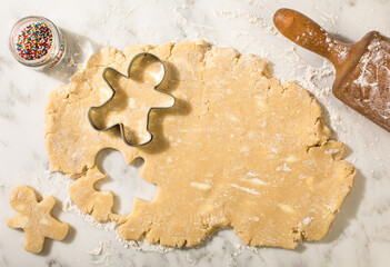 Sugar cookie dough with snowman cookie cutters and rolling pin
