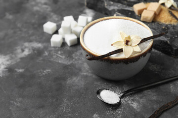 Bowl of aromatic vanilla sugar, flower and sticks on black background