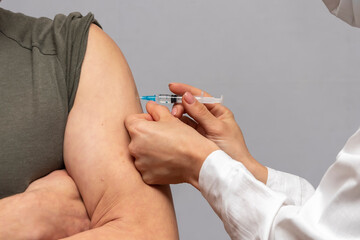 A man in a soldier's uniform is being injected in the shoulder.