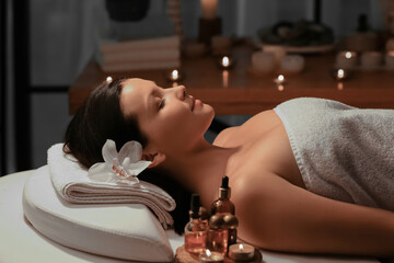 Beautiful young woman relaxing in dark spa salon