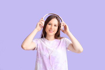 Young woman in headphones on lilac background