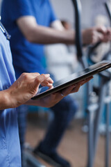 Healthcare specialist in blue scrubs and a stethoscope is closely examining a patient report on a...