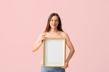 Young woman with blank frame on pink background