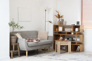 Modern living room interior with grey sofa, warm blanket and cup of tea on coffee table