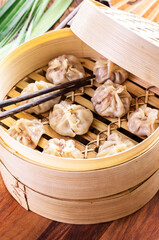 Traditional Chinese dim sum dumpling with mincemeat filling served as close-up in a bambus steamer...
