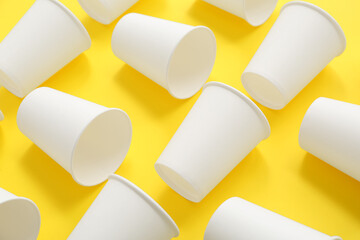 Disposable eco cups on yellow background, closeup