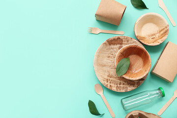 Disposable eco tableware with leaves on turquoise background