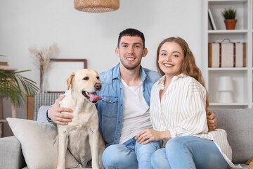 Happy young couple with Labrador dog sitting on sofa at home