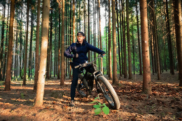 Man on an electric bike with thick wheels. Location pine forest. Healthy sports hobby. Black...
