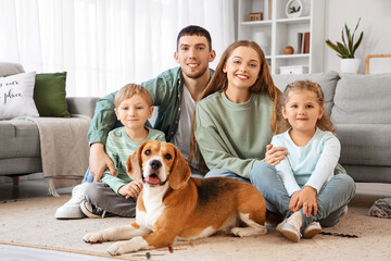 Little children with their parents and Beagle dog lying on floor at home