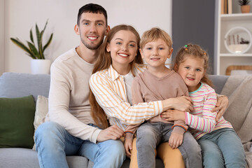 Little children with their parents hugging on sofa at home