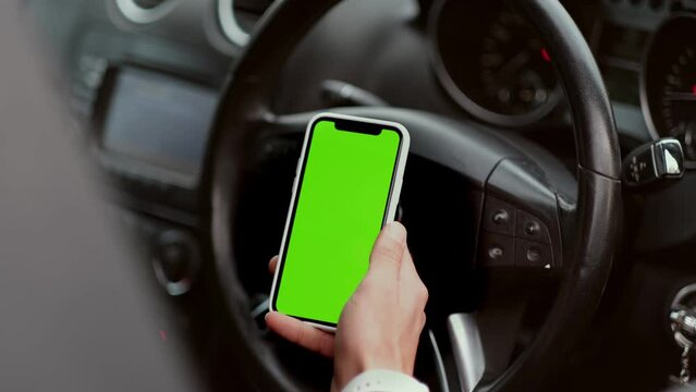 Close up of a man's hand holding a mobile telephone with a vertical green screen in car chroma key smartphone technology cell phone street touch message display hand.