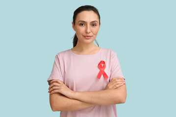 Young woman with crossed arms and red ribbon on blue background. AID awareness concept